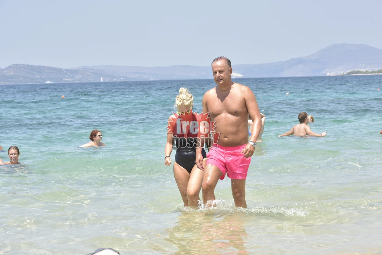 Η Μαρία Μπεκατώρου με μαύρο ολόσωμο μαγιό και ο σύζυγός της με ροζ σορτς βγαίνουν μαζί από τη θάλασσα